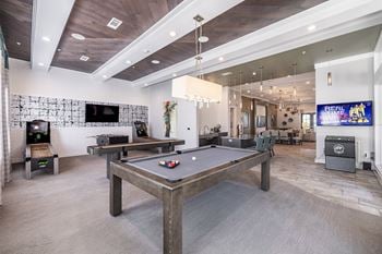 A room with a pool table and a TV mounted on the wall.